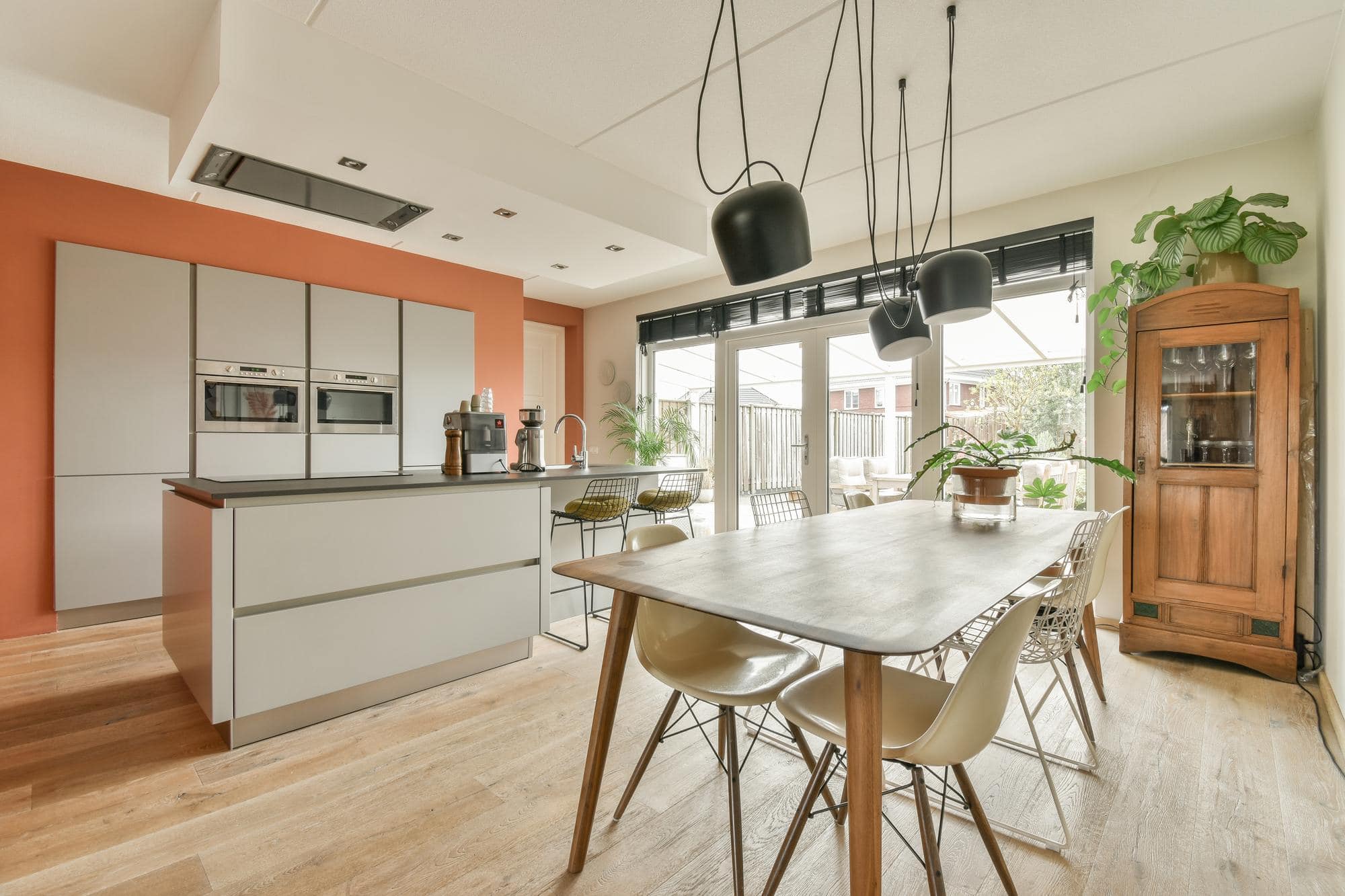 Cuisine moderne ouverte blanche et corail avec aménagement contemporain.
