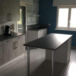 Cuisine en béton clair avec un plan de travail effet pierre, offrant un style moderne et épuré.