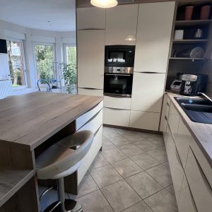 Cuisine laquée blanche équipée avec un plan de travail en bois, associant modernité et chaleur naturelle.