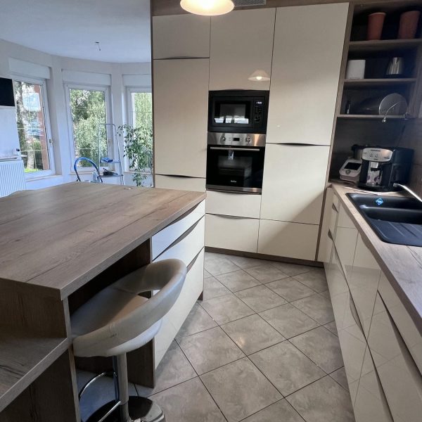 Cuisine laquée blanche équipée avec un plan de travail en bois, associant modernité et chaleur naturelle.