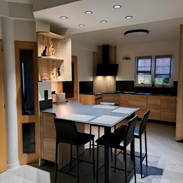 Cuisine moderne et fonctionnelle avec des meubles en bois et un plan de travail noir, alliant design naturel et élégance contemporaine.