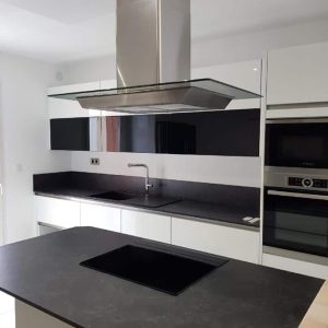 Cuisine sans poignées laquée blanche brillante avec un plan de travail effet pierre, combinant élégance minimaliste et matériaux naturels.