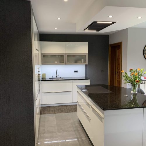 Cuisine contemporaine blanche avec plan de travail en granit et table en verre
