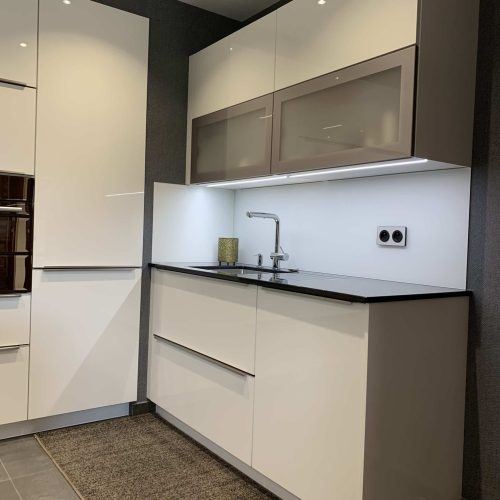 Cuisine contemporaine blanche laquée avec plan de travail en granit noir et table à manger en verre