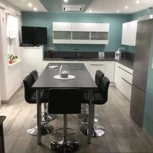 Cuisine laquée blanche brillante avec un plan de travail effet béton, associant modernité et contraste élégant.