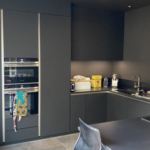 Cuisine moderne sans poignées avec façades Fenix noir mat et plan de travail en céramique assortie