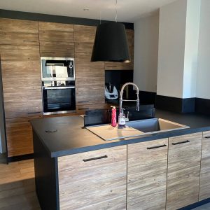 Cuisine moderne équipée avec des façades en bois et un plan de travail foncé, combinant chaleur naturelle et élégance contemporaine.