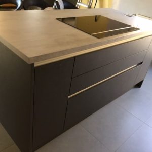 Cuisine sans poignées en béton foncé avec un plan de travail effet béton, alliant design épuré et modernité industrielle.